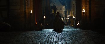 Movie still from “The Three Musketeers” (2011), directed by Paul W.S. Anderson – A woman sitting on the side of a road at night; Wide shot, High angle
