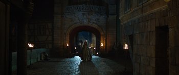 Movie still from “The Three Musketeers” (2011), directed by Paul W.S. Anderson – A person sitting in front of an archway at night; Extreme Wide shot, Over the shoulder angle