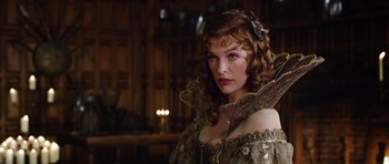 Movie still from “The Three Musketeers” (2011), directed by Paul W.S. Anderson – A woman with long red curly hair wearing a gold dress; Close Up shot, Over the shoulder angle