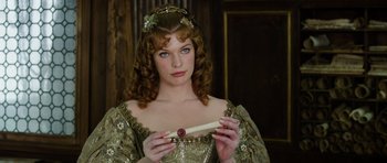 Movie still from “The Three Musketeers” (2011), directed by Paul W.S. Anderson – A beautiful woman in a green dress holding a candle in her hand; Close Up shot, Over the shoulder angle