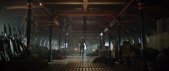 Movie still from “The Three Musketeers” (2011), directed by Paul W.S. Anderson – A man holding a gun in a room with wooden pillars; Wide shot, Low angle