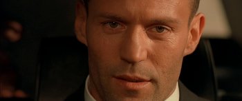 Movie still from “The Transporter” (2002), directed by Corey Yuen – A man in a suit looking at the camera; Extreme Close Up shot, Over the shoulder angle