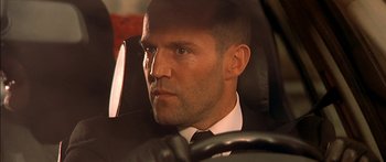 Movie still from “The Transporter” (2002), directed by Corey Yuen – A person wearing a suit and tie in a car; Close Up shot, Low angle