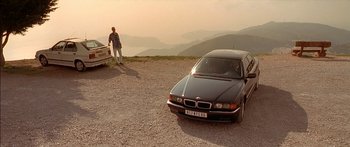Movie still from “The Transporter” (2002), directed by Corey Yuen – A man standing next to a car on top of a hill; Extreme Wide shot, Low angle