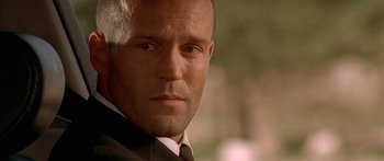 Movie still from “The Transporter” (2002), directed by Corey Yuen – A person wearing a suit and tie; Close Up shot, Low angle