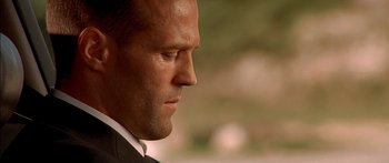 Movie still from “The Transporter” (2002), directed by Corey Yuen – A person wearing a suit looking down; Close Up shot, Low angle