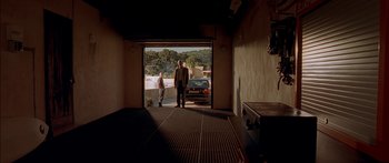 Movie still from “The Transporter” (2002), directed by Corey Yuen – Two men standing in a garage with a car in the background; Extreme Wide shot, Low angle