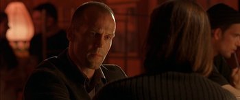 Movie still from “The Transporter” (2002), directed by Corey Yuen – A man in a suit and tie talking to a woman; Close Up shot, Over the shoulder angle