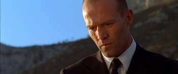 Movie still from “The Transporter” (2002), directed by Corey Yuen – A man in a suit and tie looking to his left; Close Up shot, Low angle
