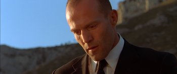 Movie still from “The Transporter” (2002), directed by Corey Yuen – A man in a black suit and a black tie; Close Up shot, Low angle