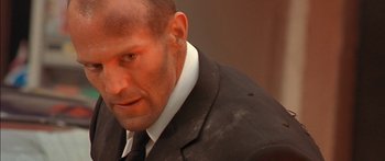 Movie still from “The Transporter” (2002), directed by Corey Yuen – A person wearing a suit and tie; Close Up shot, Low angle
