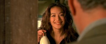 Movie still from “The Transporter” (2002), directed by Corey Yuen – A woman smiling while holding a bottle of hair conditioner; Close Up shot, Over the shoulder angle