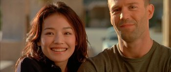 Movie still from “The Transporter” (2002), directed by Corey Yuen – A man and a woman smiling for the camera; Close Up shot, Low angle