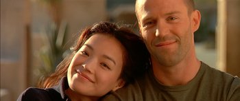 Movie still from “The Transporter” (2002), directed by Corey Yuen – A man and a woman smile for a picture; Close Up shot, Low angle