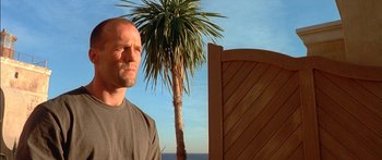 Movie still from “The Transporter” (2002), directed by Corey Yuen – A man standing in front of a palm tree; Close Up shot, Low angle