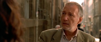 Movie still from “The Transporter” (2002), directed by Corey Yuen – An older man wearing a suit and a striped shirt; Close Up shot, Low angle
