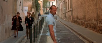 Movie still from “The Transporter” (2002), directed by Corey Yuen – A man standing on the side of a street; Medium shot, Low angle