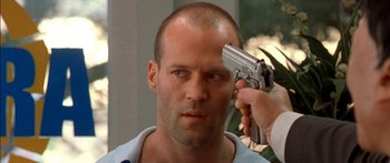 Movie still from “The Transporter” (2002), directed by Corey Yuen – A man holding a gun up to his head; Close Up shot, Over the shoulder angle