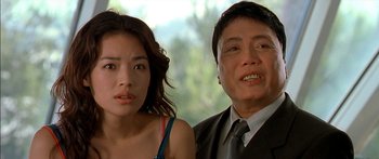 Movie still from “The Transporter” (2002), directed by Corey Yuen – A man and a woman standing next to each other in front of a window; Close Up shot, Low angle