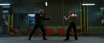 Movie still from “The Transporter” (2002), directed by Corey Yuen – Two men are practicing martial arts in an industrial setting; Wide shot, Low angle