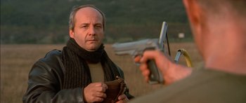 Movie still from “The Transporter” (2002), directed by Corey Yuen – A man in a scarf is holding a gun; Close Up shot, Low angle