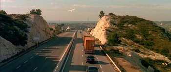 Movie still from “The Transporter” (2002), directed by Corey Yuen – An airplane flying over a highway with cars on it; Extreme Wide shot, High angle