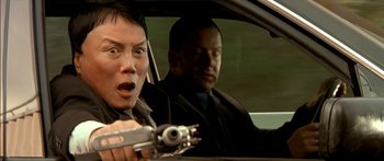 Movie still from “The Transporter” (2002), directed by Corey Yuen – A man in a car holding a gun with another man in a car behind him; Close Up shot, Low angle