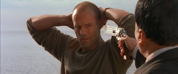 Movie still from “The Transporter” (2002), directed by Corey Yuen – A bald man holding a gun in his hands; Close Up shot, Low angle