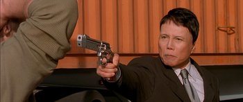 Movie still from “The Transporter” (2002), directed by Corey Yuen – A man holding a gun pointed to the ground; Close Up shot, Low angle