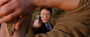 Movie still from “The Transporter” (2002), directed by Corey Yuen – A man holding a gun up to his face; Close Up shot, Over the shoulder angle
