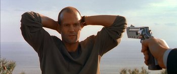 Movie still from “The Transporter” (2002), directed by Corey Yuen – A man with a shaved head is posing for a picture; Close Up shot, Low angle