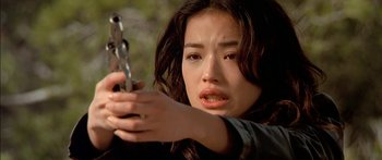 Movie still from “The Transporter” (2002), directed by Corey Yuen – A young woman holding a gun in her hand; Close Up shot, Low angle