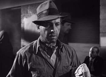Movie still from “The Treasure of the Sierra Madre” (1948), directed by John Huston – A man wearing a hat is smoking a cigarette; Close Up shot, Low angle