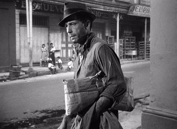 Movie still from “The Treasure of the Sierra Madre” (1948), directed by John Huston – A black and white photo of a man walking down the street; Medium shot, Low angle