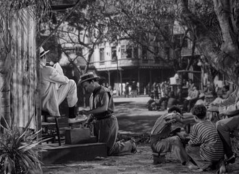 Movie still from “The Treasure of the Sierra Madre” (1948), directed by John Huston – A group of men sitting on a bench in the street; Wide shot, Low angle