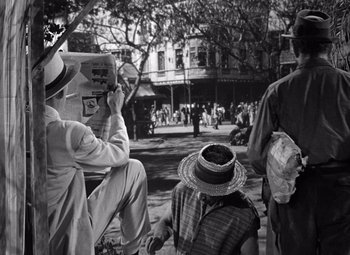 Movie still from “The Treasure of the Sierra Madre” (1948), directed by John Huston – A group of people sitting on the ground in the street; Wide shot, High angle