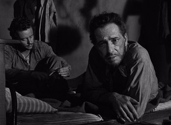 Movie still from “The Treasure of the Sierra Madre” (1948), directed by John Huston – Two men sitting on the ground looking at the camera; Medium shot, Low angle