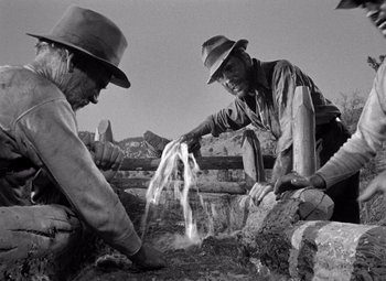 Movie still from “The Treasure of the Sierra Madre” (1948), directed by John Huston – A couple of men in hats are working on a project; Medium shot, High angle