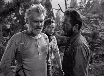 Movie still from “The Treasure of the Sierra Madre” (1948), directed by John Huston – A black - and - white photo of three men talking; Medium shot, Over the shoulder angle