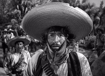 Movie still from “The Treasure of the Sierra Madre” (1948), directed by John Huston – A man with a large hat is standing next to another man; Medium shot, Low angle