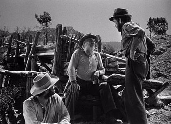 Movie still from “The Treasure of the Sierra Madre” (1948), directed by John Huston – A group of men sitting next to each other on top of a field; Wide shot, Over the shoulder angle
