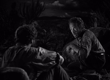 Movie still from “The Treasure of the Sierra Madre” (1948), directed by John Huston – A man and a woman sitting on the ground in the dark; Medium shot, Over the shoulder angle