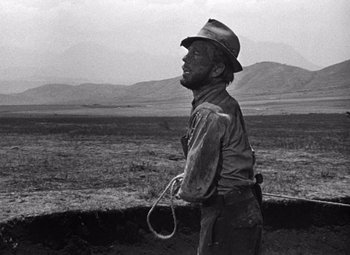 Movie still from “The Treasure of the Sierra Madre” (1948), directed by John Huston – An old photo of a man holding a lasso; Medium shot, Over the shoulder angle