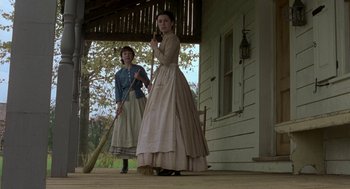 Movie still from “The Village” (2004), directed by M. Night Shyamalan – Two women dressed in old fashion clothing holding a broom; Wide shot, Low angle
