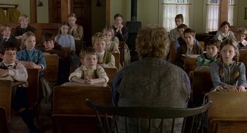 Movie still from “The Village” (2004), directed by M. Night Shyamalan – A group of people sitting in a room with a woman; Wide shot, High angle