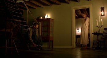Movie still from “The Village” (2004), directed by M. Night Shyamalan – A man sitting on the stairs in a room; Wide shot, Low angle
