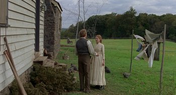 Movie still from “The Village” (2004), directed by M. Night Shyamalan – A man and a woman standing next to each other in a field; Wide shot, Over the shoulder angle