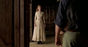 Movie still from “The Village” (2004), directed by M. Night Shyamalan – A woman in a long white dress standing in a room; Medium shot, Over the shoulder angle
