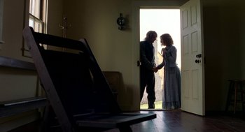 Movie still from “The Village” (2004), directed by M. Night Shyamalan – A man and a woman holding hands in a doorway; Wide shot, Low angle