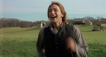 Movie still from “The Village” (2004), directed by M. Night Shyamalan – A man with long hair and a beard is smiling; Medium shot, Low angle